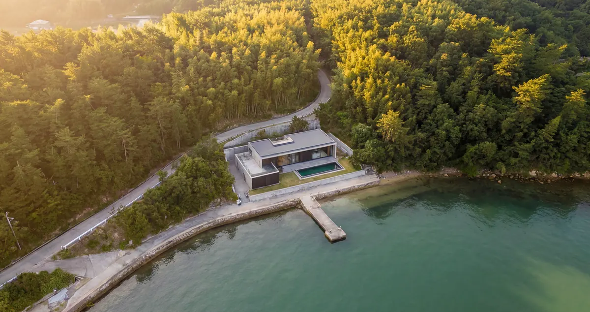 Naoshima House, aerial view of the concrete house on the wooded shore, with its jetty